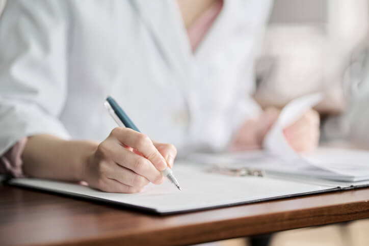 A medical office graduate sitting in an office writing on a board after medical office specialist training