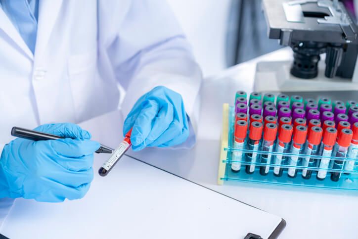 A phlebotomist labelling and documenting blood sample vials after medical office specialist training